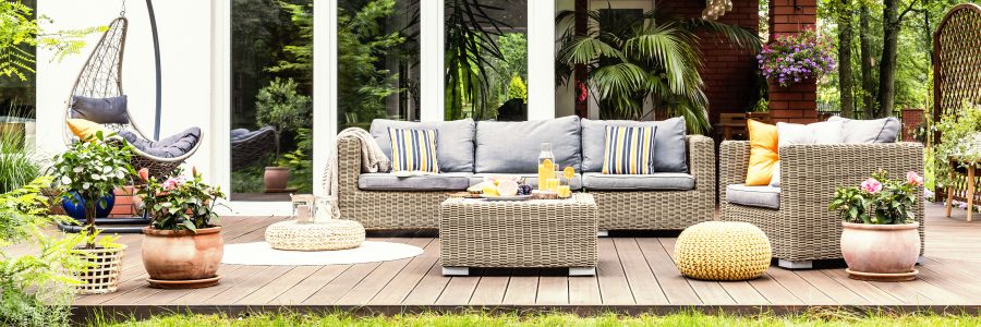 A Relaxing Spot For A Warm, Summer Day   A Stylish, Wooden Terrace With Wicker Garden Furniture, Cushions, Plants And Flowers